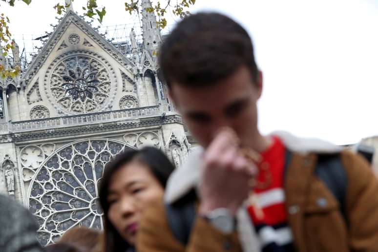 People pray near Notre-Dame Cathedral after a massive fire devastated large parts of the gothic structure in Paris, France April 16, 2019. REUTERS/Yves Herman