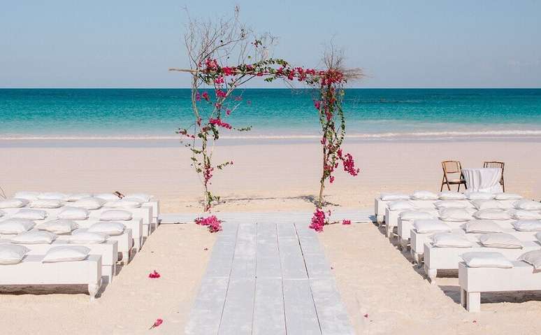 4. Noivado na praia com decoração simples e romântica com um simples arco rústico decorado com flores para o altar – Foto: Kallima Photography