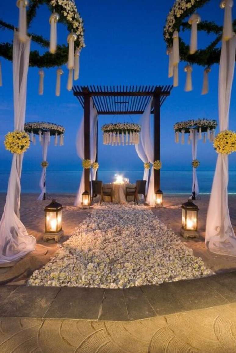 52. Decoração sofisticada com arranjo de flores e velas para casamento na praia de noite – Foto: Wedding Ideas