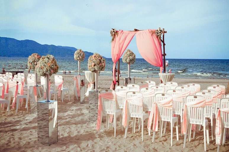 33. Alguns noivos querem levar o luxo dos arranjos de flores para a decoração de casamento na praia
