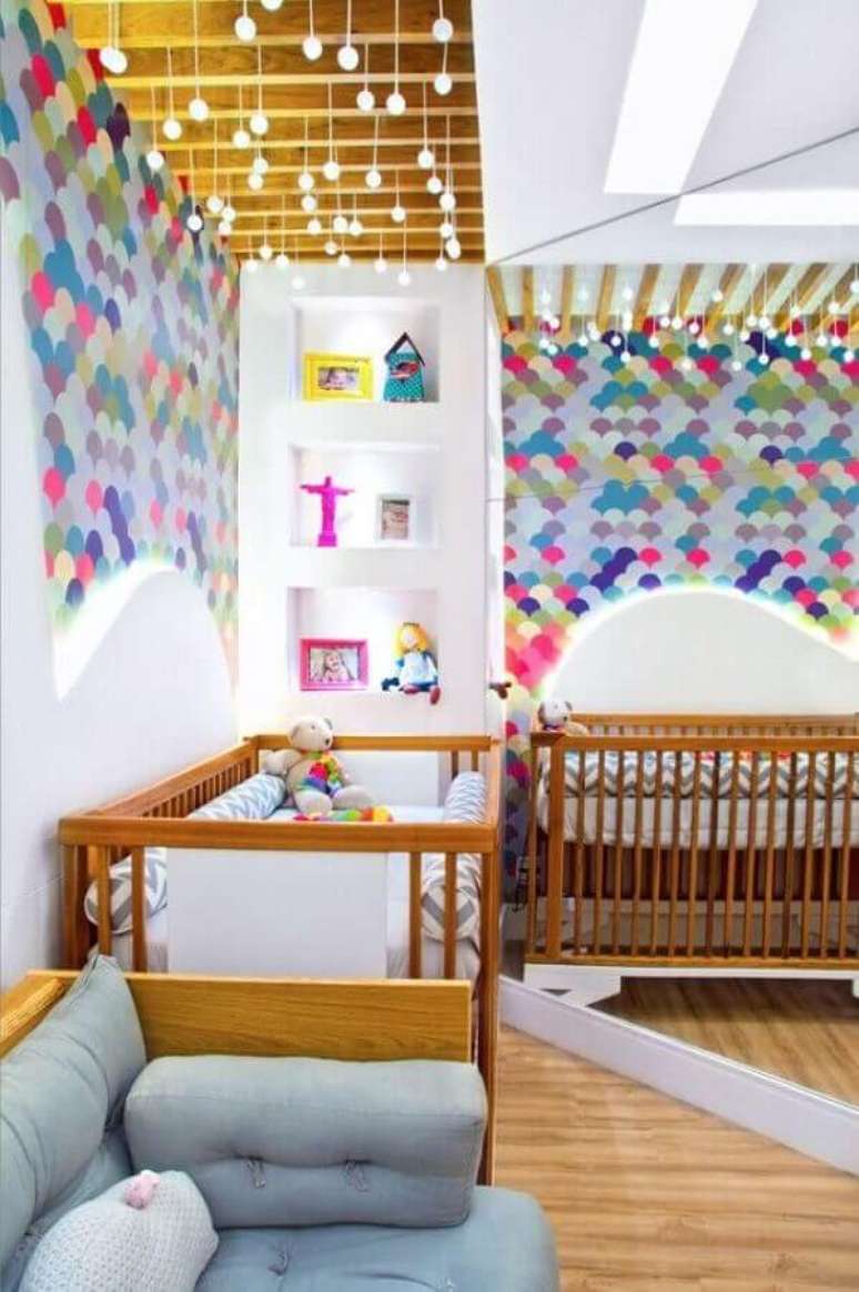 54. Papel de parede colorido dando mais personalidade para o quarto de gêmeos com berço de madeira – Foto: Classy World