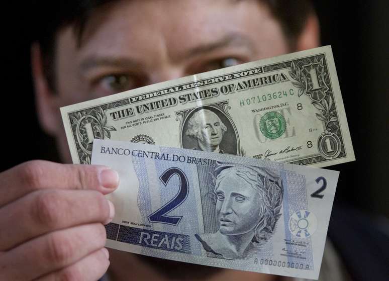 Homem segura notas de 1 dólar e 2 reais
13/12/2001
REUTERS/Gregg Newton