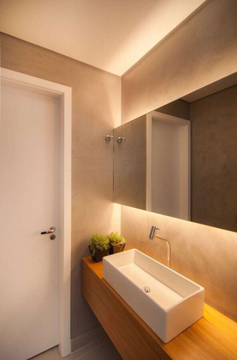 30. Espelho para lavabo decorado em tons neutros com bancada de madeira – Foto: Diseno Interior