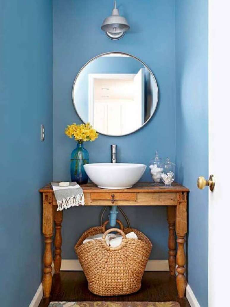 47. Decoração simples com espelho redondo para lavabo com móvel de madeira e parede azul – Foto: Julie Holloway Studio