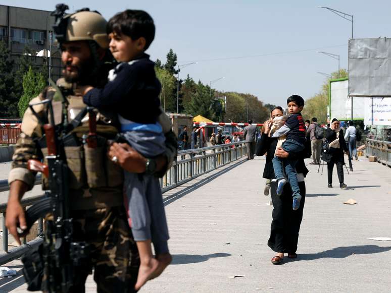 Um soldado e uma mulher carregam crianças resgatadas de um edifício do Ministério das Comunicações em Kabul, no Afeganistão, que foi alvo de um ataque de um homem-bomba. 20/4/2019. REUTERS/Mohammad Ismail