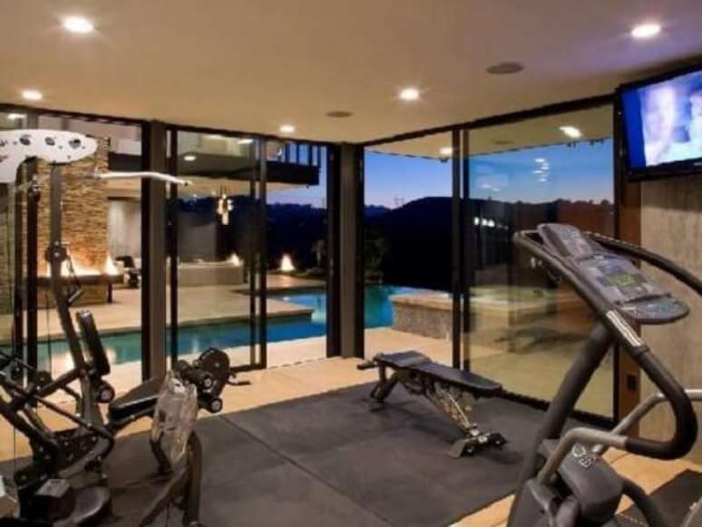 40- A decoração academia em casa tem portas de correr em vidro para visualizar o espaço da piscina. Fonte: Fonte Decoração I