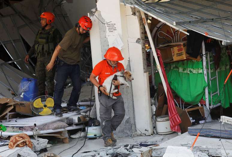 Socorrista carrega c&atilde;o usado nas buscas em pr&eacute;dio que desabou ap&oacute;s terremoto nas Filipinas
23/04/2019 REUTERS/Eloisa Lopez 