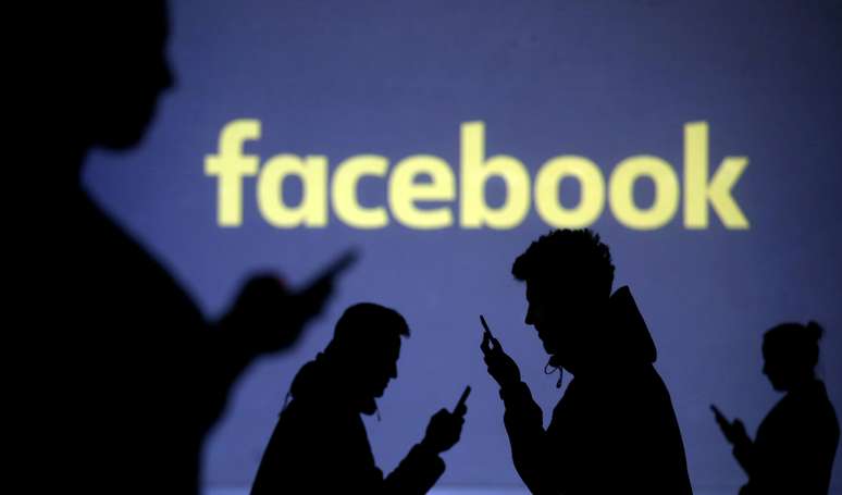 Silhuetas de usuários de smartphones é vista perto de logotipo do Facebook. 28/3/2018.  REUTERS/Dado Ruvic/Illustration