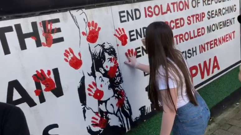 Mulheres espalham tinta vermelha em frente à sede de um grupo político ligado ao Novo IRA