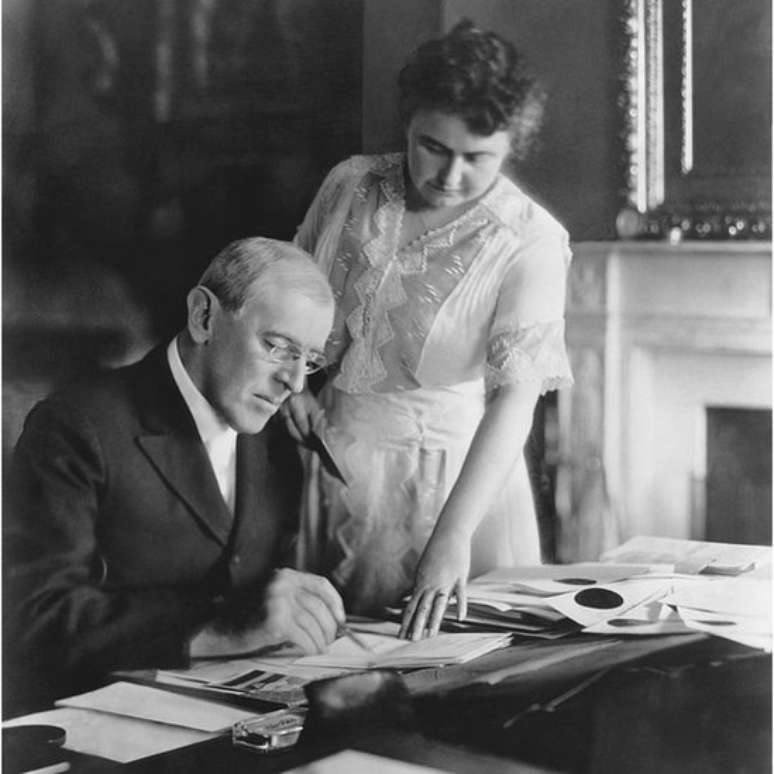 Primeira-dama Edith Wilson ajuda o presidente Woodrow Wilson em sua mesa na Casa Branca; ele sofreu de depress&atilde;o profunda