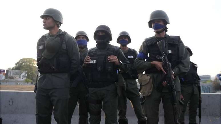 Integrantes de forças militares usando braçadeira azul, em apoio a Guaidó