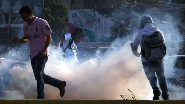 Venezuelanos fogem das bombas de gás lacrimogêneo lançadas pelas forças de segurança em Caracas