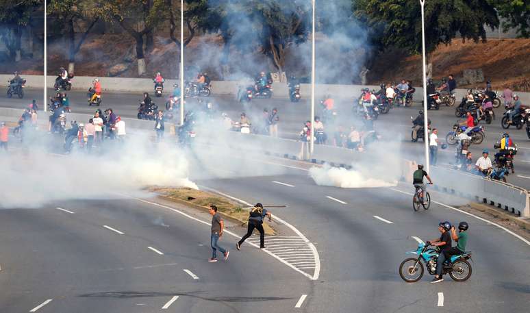 Pessoas reagem ao disparo de gás lacrimogêneo perto de base aérea em Caracas
30/04/2019 REUTERS/Carlos Garcia Rawlins