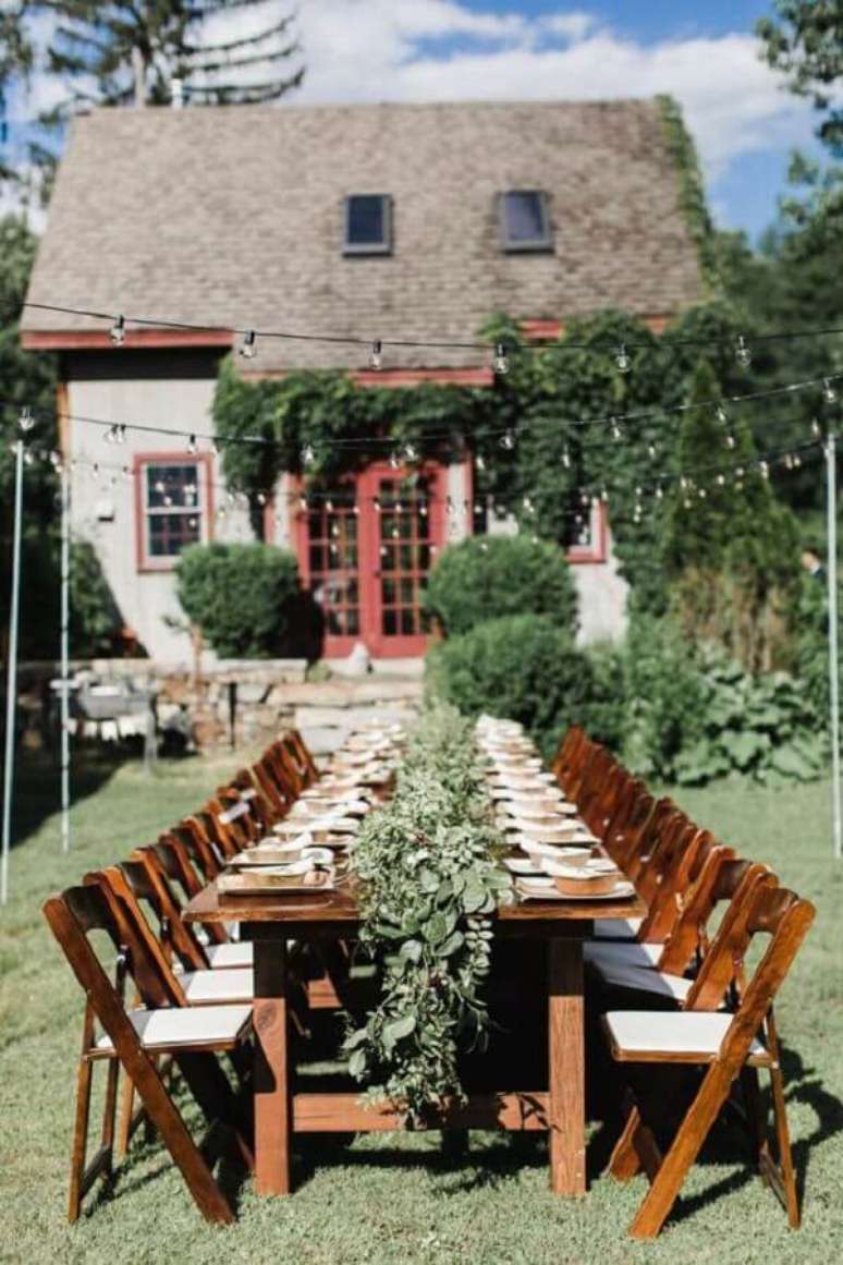 41. Decoração de festa de casamento ao ar livre com varal de luz e arranjo de folhas sobre a mesa dos convidados – Foto: Pinterest