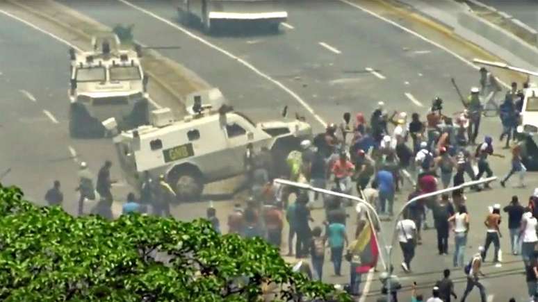 Um carro blindado avança contra manifestantes nas ruas de Caracas