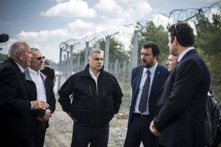 Viktor Orbán (centro) e Matteo Salvini (à sua esquerda) conversam em frente a barreira antimigrantes na Hungria