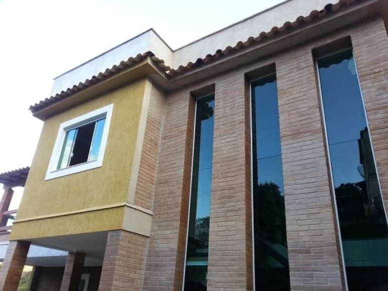 20- A casa de tijolo ecológico com pé direito duplo tem vidros grandes na fachada. Fonte: Makeem Foco