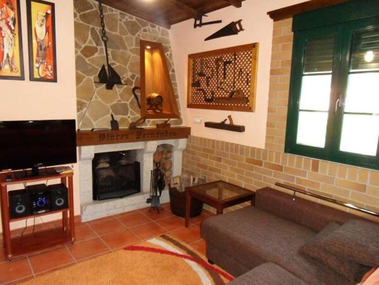 27- Na decora&ccedil;&atilde;o da casa r&uacute;stica, as pedras revestem a lareira. Fonte: Booking