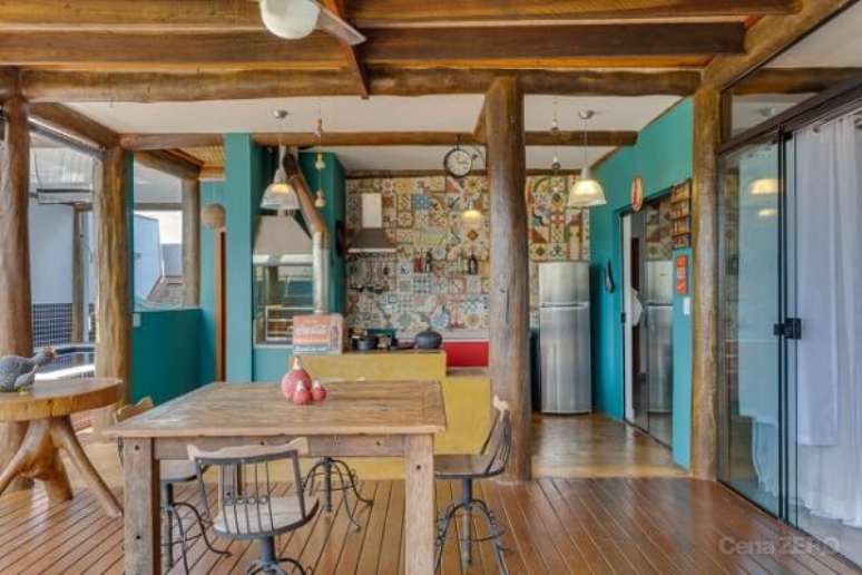 29- Na casa r&uacute;stica, a &aacute;rea gourmet tem pilares e vigas em madeira. Fonte: Cena Zero