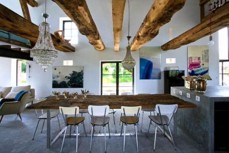 33- As madeiras rústicas irregulares da mesa, do teto e mezanino harmonizam com o cimento queimado do piso e da bancada na casa rústica. Fonte: Casa Vogue