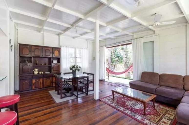 52- A casa r&uacute;stica de madeira tem as paredes e o forro pintadas de branco. Fonte: Booking