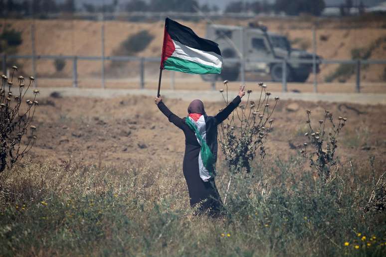 Mulher segura bandeira palestina em frente a forças israelenses no sul da Faixa de Gaza
15/05/2019 REUTERS/Ibraheem Abu Mustafa 