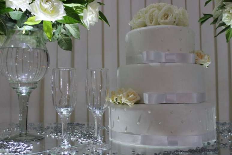 15- Sobre a mesa de vidro, a decoração bodas de prata tem confeitos prateados jogados aleatoriamente. Fonte: Buffet Cortello