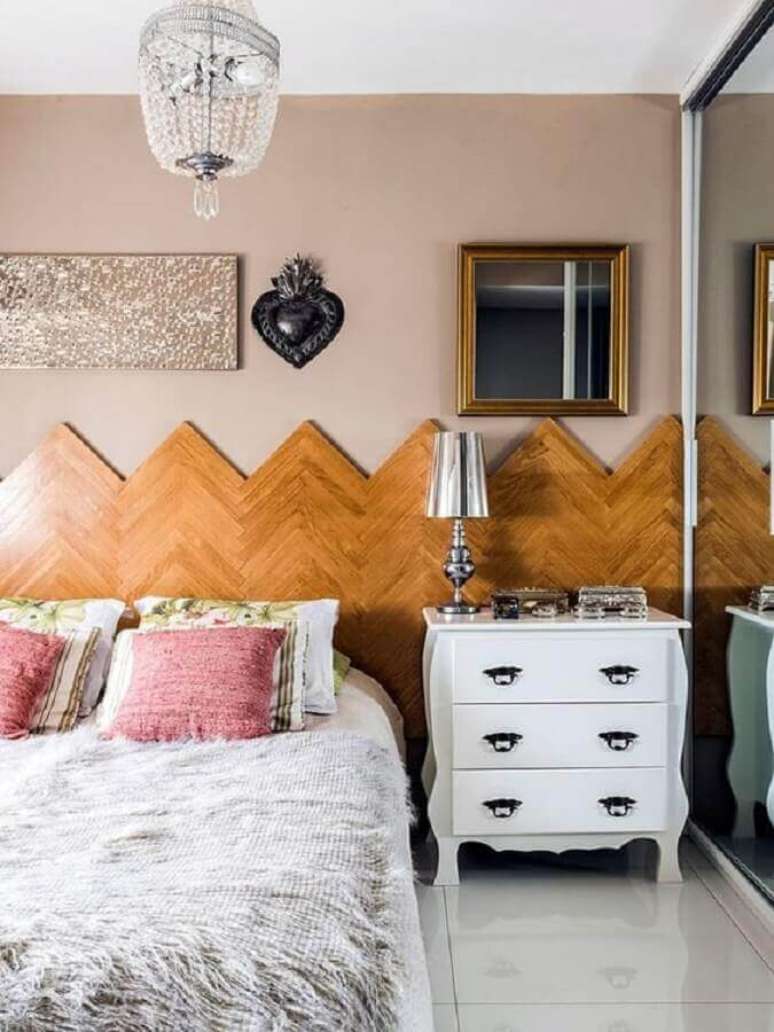 31. Decoração com abajur todo metalizado para decoração de quarto com cabeceira de madeira e lustre de cristal – Foto: Casa de Valentina