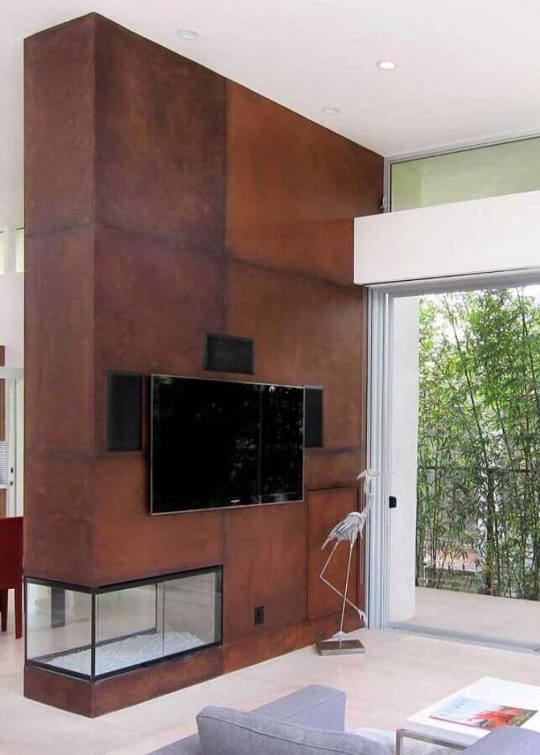 50. Sala de TV decorada com porcelanato aço corten e lareira de canto – Foto: Pinosy