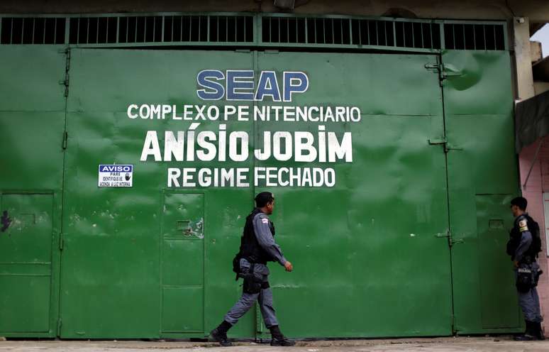 Policiais caminham em frente à entrada principal do Compaj, em Manaus