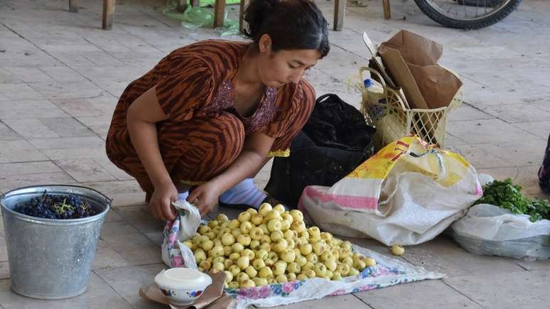 Vendedora de maçãs em Bukhara, vendendo uma variedade amarela cultivada no Uzbequistão