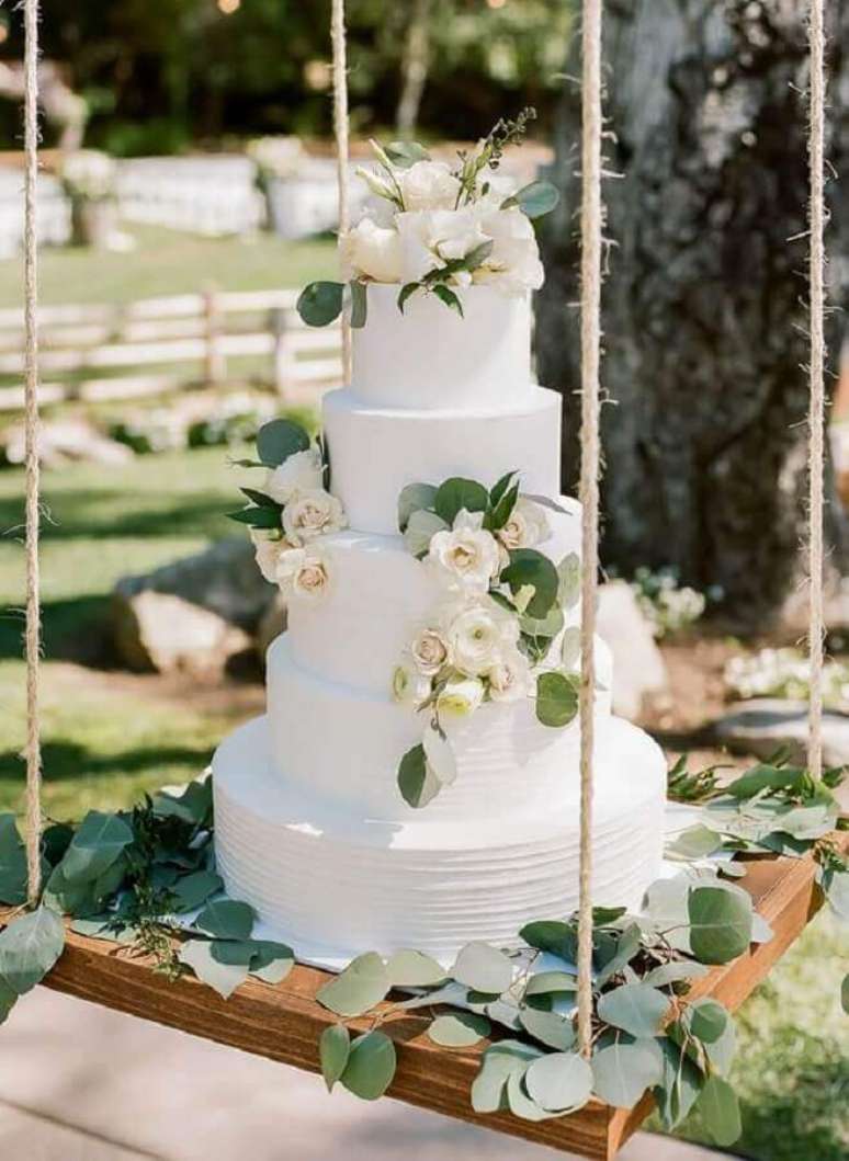 22. Lindo bolo bodas de pérola decorado com rosas brancas sobre balanço com folhagens – Foto: Michelle Garibay Events