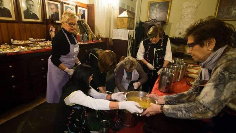 Mulheres preparam comida para pessoas sem-teto durante um evento natalino de caridade