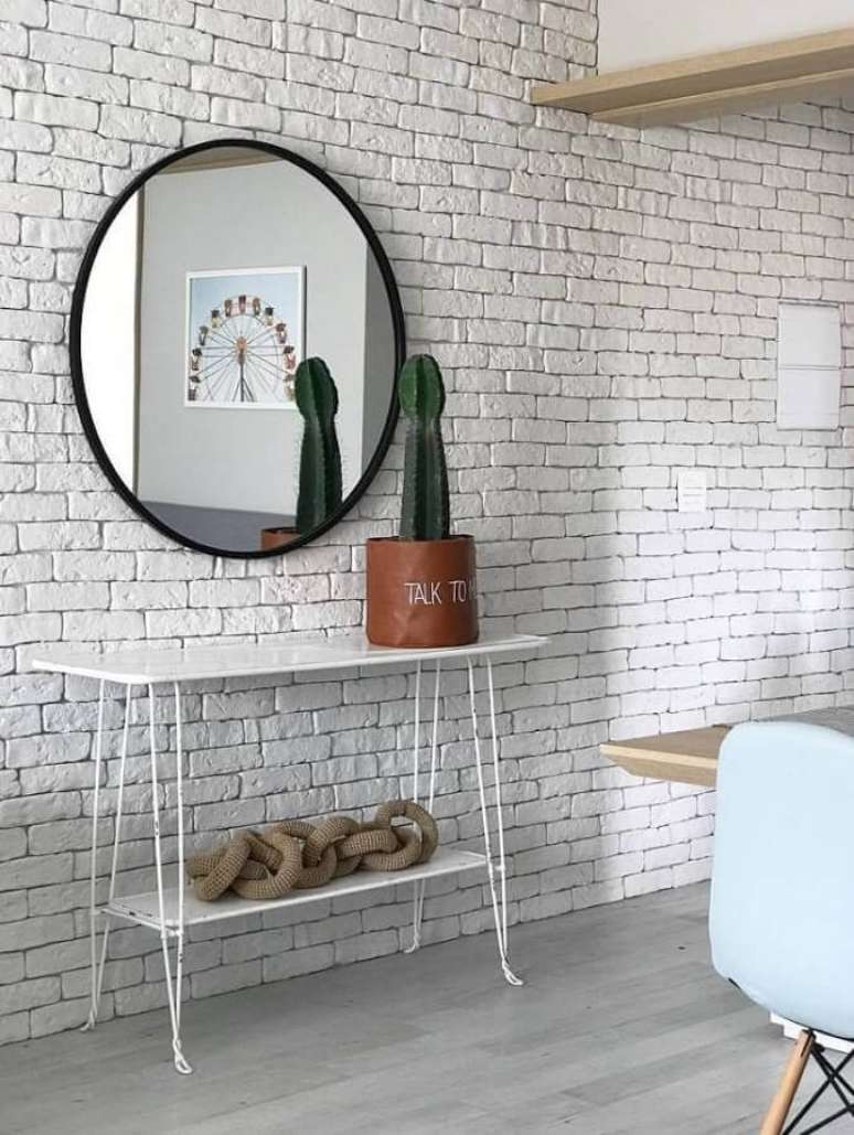 21. Decoração minimalista com espelho redondo com moldura preta para parede branca de tijolinho – Foto: Duda Senna