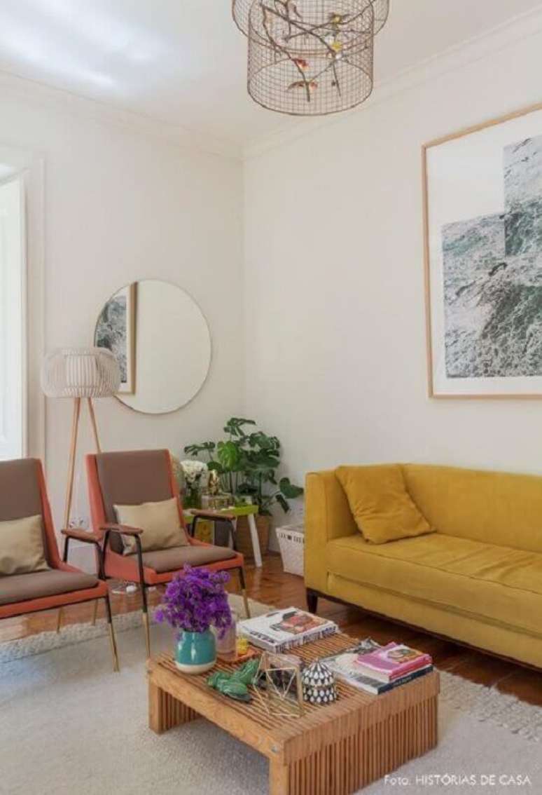 4. Decoração clean com sofá amarelo e espelho redondo para sala de estar – Foto: Histórias de Casa