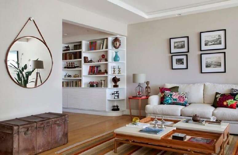 42. Sala ampla decorada com sof&aacute; branco e espelho redondo com al&ccedil;a de couro sobre ba&uacute; antigo &ndash; Foto: Da Hora Arquitetura