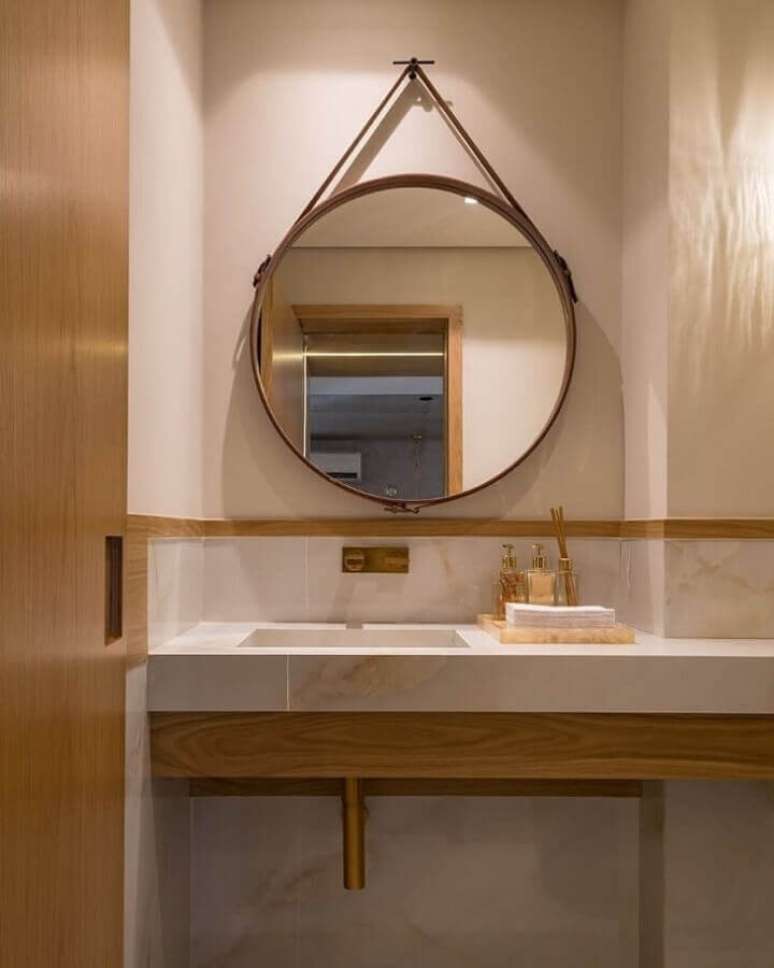 55. Espelho redondo com couro para decoração de banheiro em tons neutros – Foto: Ferrassa & Pickler Arquitetura