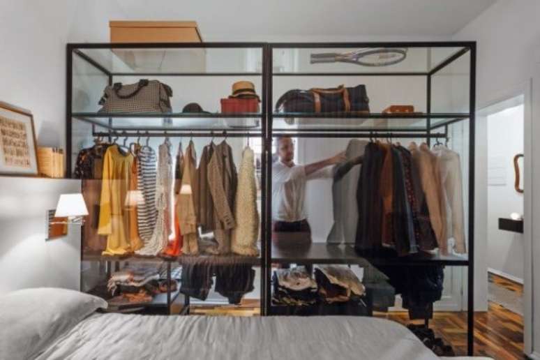 32. Para esse quarto pequeno, o closet aramado ganhou uma parede de vidro como medida para dividir os ambientes sem diminuir o espa&ccedil;o.