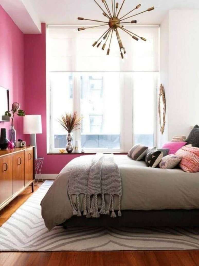 46. Lustre moderno para quarto de casal com parede rosa e móveis de madeira – Foto: Design Innova