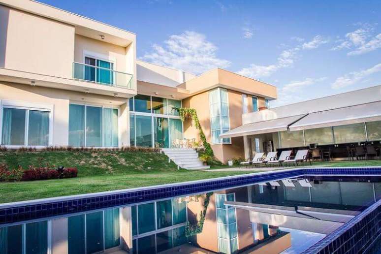 38. Casa bonita, com piscina, área externa de lazer e janelas grandes na casa. Projeto por Haus Arquitetura