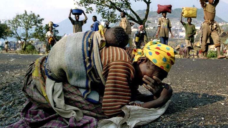 Mulher desaba aos prantos, com o bebê nas costas, após fugir de Ruanda em 1994