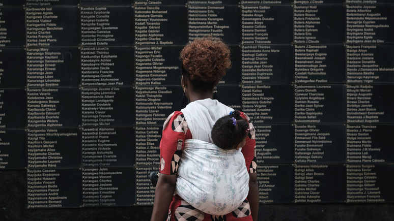Mulher observa mural com o nome das vítimas do genocídio, que completa 25 anos