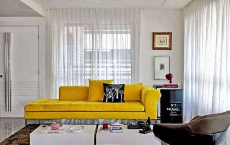 38. Sala de estar decorada com sofá amarelo e tonel decorativo preto com logo da Chanel – Foto: Ingrid Raggio