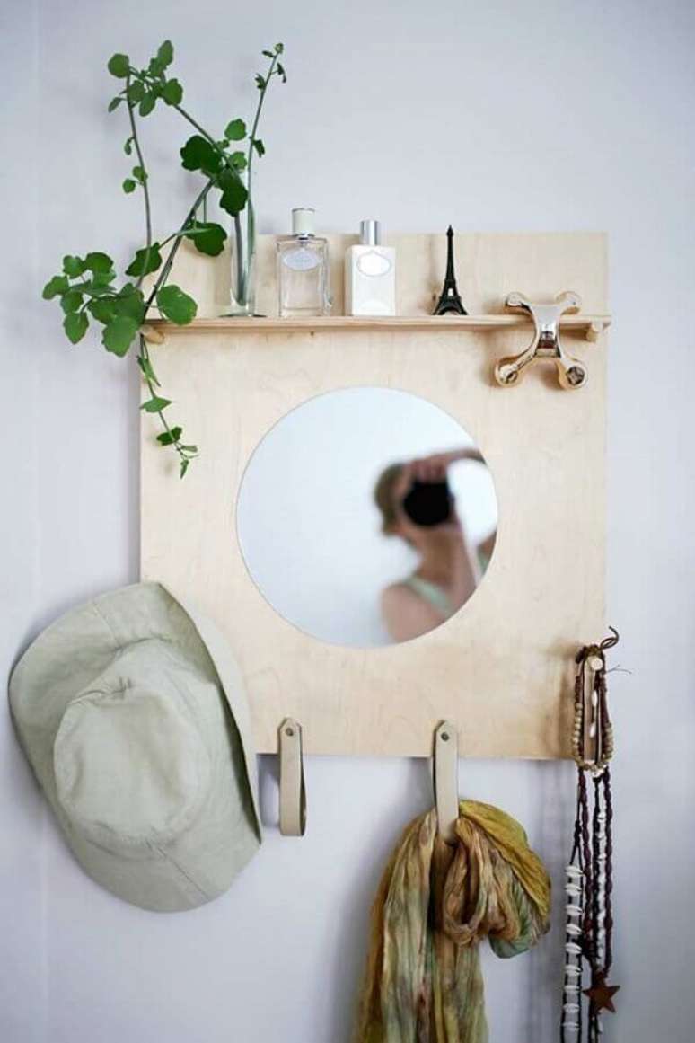 24. Aqui o cabideiro de madeira para parede ganhou um toque especial com um espelho redondo no centro – Foto: Otimizi