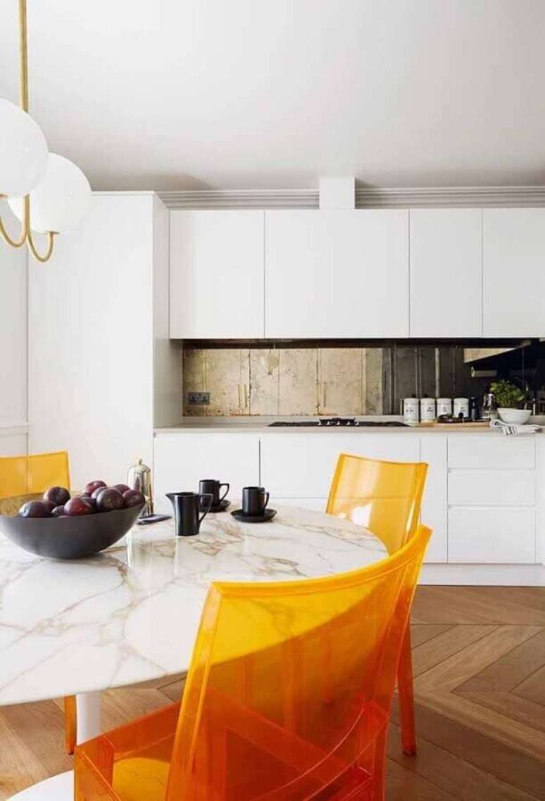 7. Decoração para cozinha branca com cadeiras de acrílico laranja dando um toque de personalidade ao ambiente – Foto House and Garden