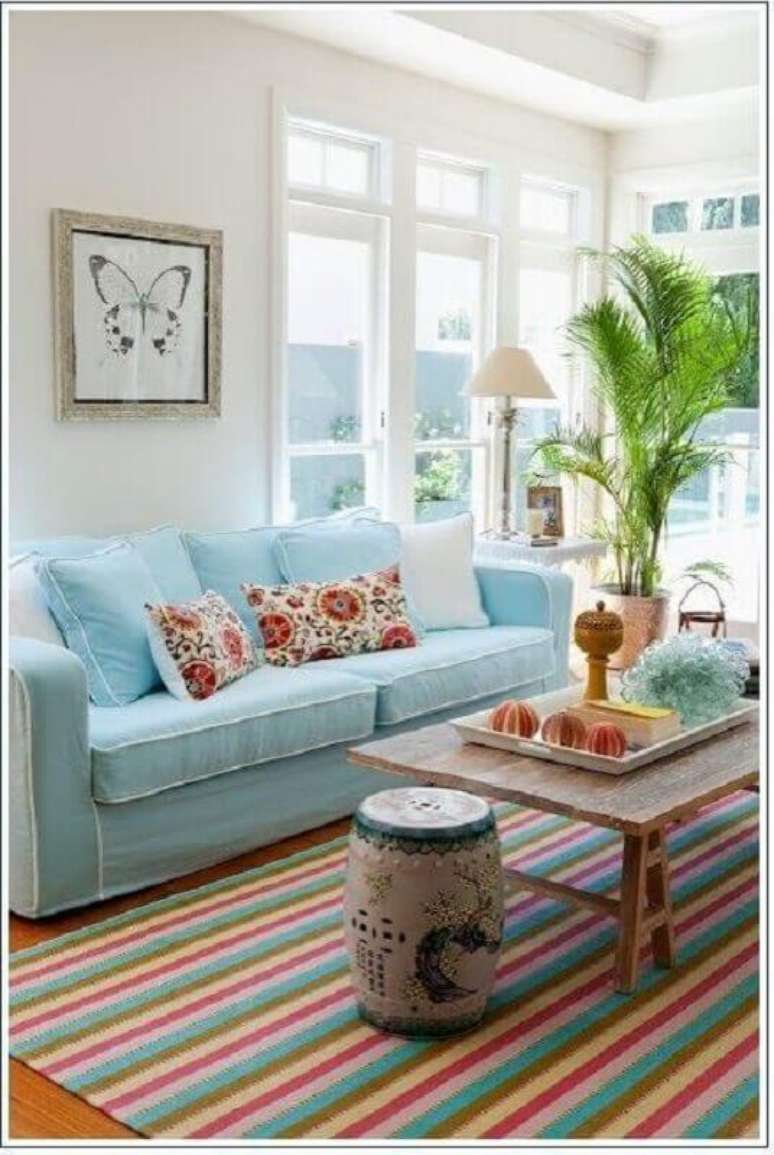 12. Decoração clean para sala com sofá azul claro e tapete listrado colorido – Foto: Pinterest