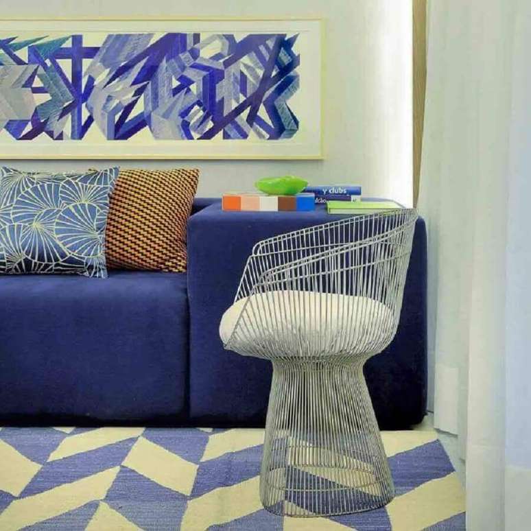 27. Sala com sofá azul decorada com cadeira moderna e tapete com estampa geométrica – Foto: Guilherme Torres