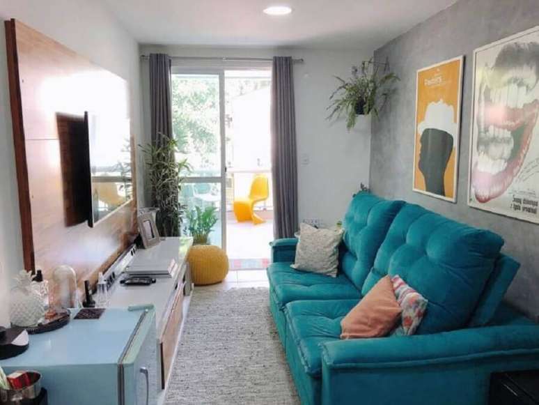 28. Decoração para sala pequena com painel de madeira e sofá retrátil azul – Foto: Apê Pieno di Vita