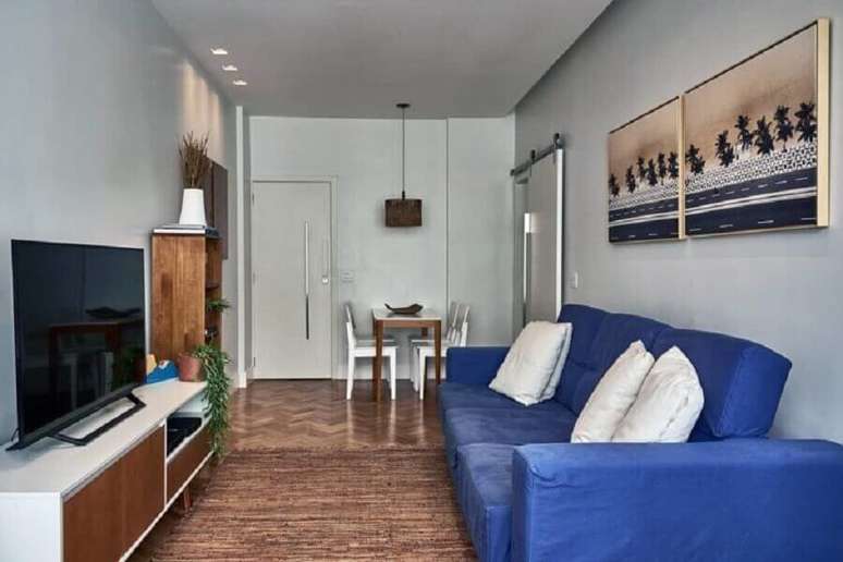 31. Sala simples decorada com rack branco e sofá azul – Foto: Aiana Comelli Arquitetura