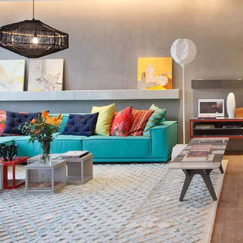 48. Decoração para sala moderna com cimento queimado, sofá azul turquesa e almofadas coloridas – Foto: Paula Neder Arquitetura